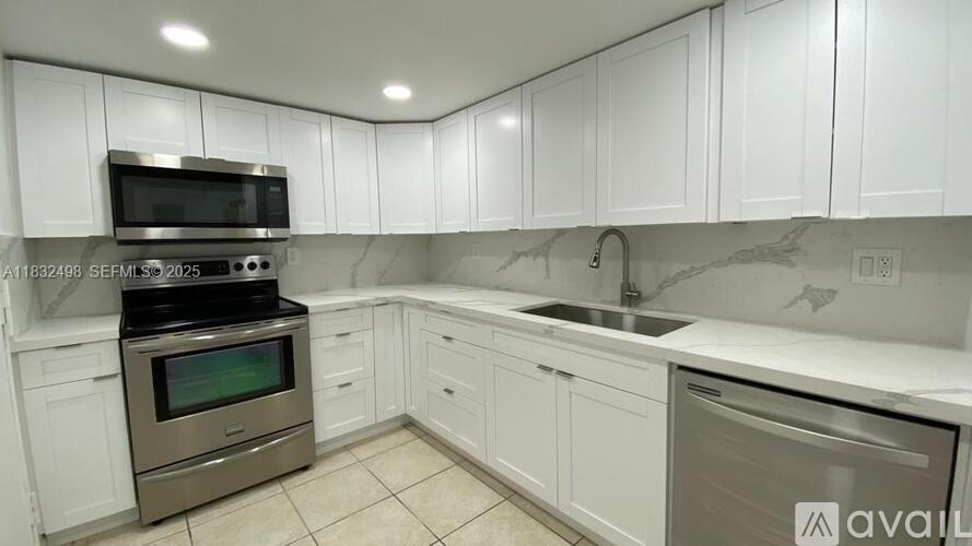 A kitchen with white cabinets and a marble countertop.