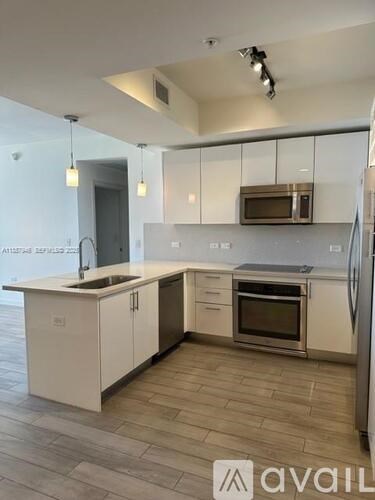 A kitchen with white cabinets and a wooden floor.