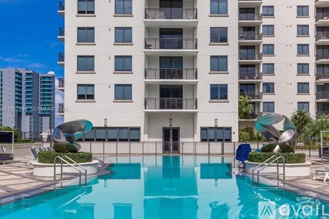 A large white apartment building with a pool in front.