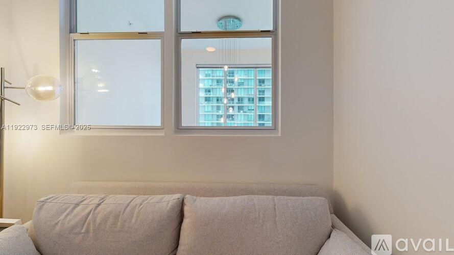 A living room with a couch and a window overlooking a building.