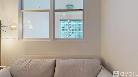 A living room with a couch and a window overlooking a building.