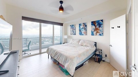 A bedroom with a large bed and a balcony overlooking the ocean.