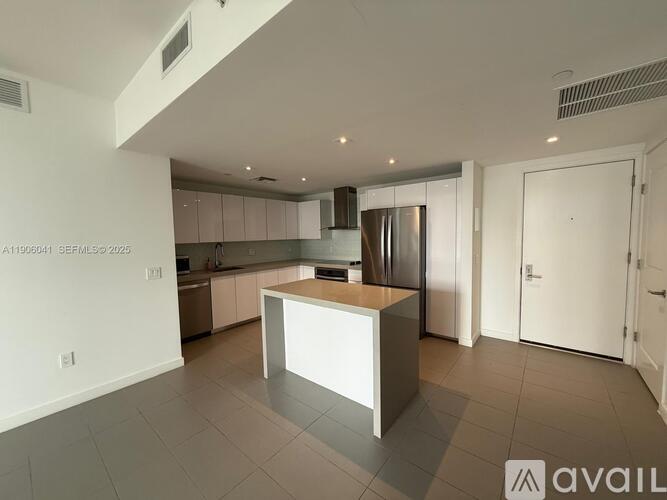 A modern kitchen with a central island and a refrigerator.