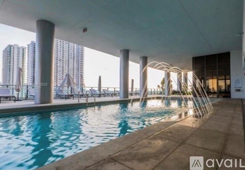 A large indoor swimming pool with a view of the city skyline.