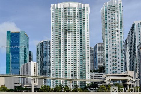 A cityscape with tall buildings and a bridge in the foreground.