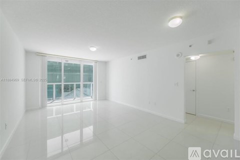 A spacious, empty room with a large window and a door on the right side.