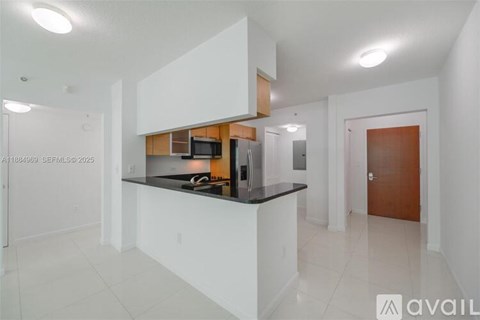 A kitchen with white cabinets and a black countertop is available for rent.