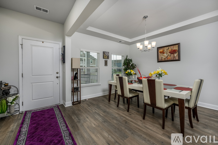 A dining room with a white door and a purple rug.