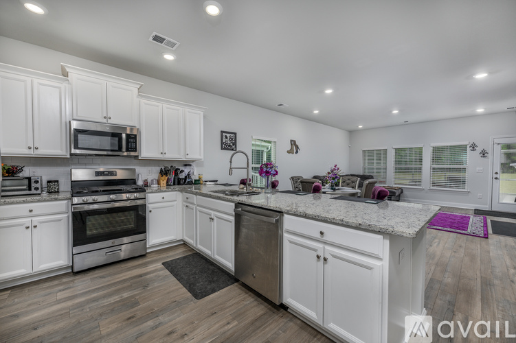 A kitchen with white cabinets and a wooden floor.