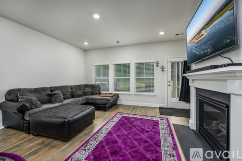 A living room with a grey sectional sofa and a purple rug.