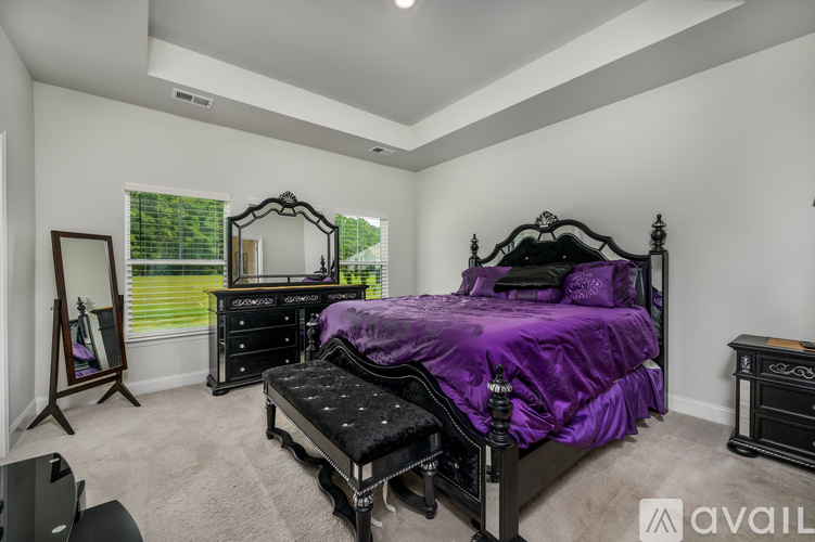 A bedroom with a purple bedspread and black furniture.
