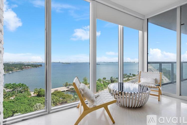 A room with a view of the water and sky through large windows.