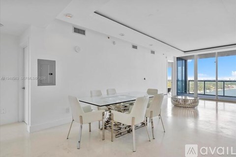 A modern dining room with a glass table and white chairs.