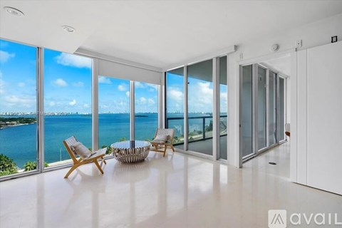 A spacious room with a view of the sea and sky through large windows.