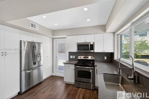 A modern kitchen with stainless steel appliances and wooden flooring.