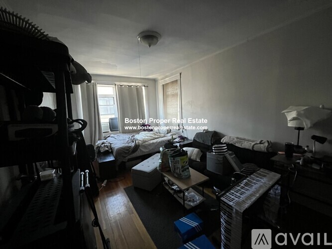 A cluttered room with a bed, desk, and chair.