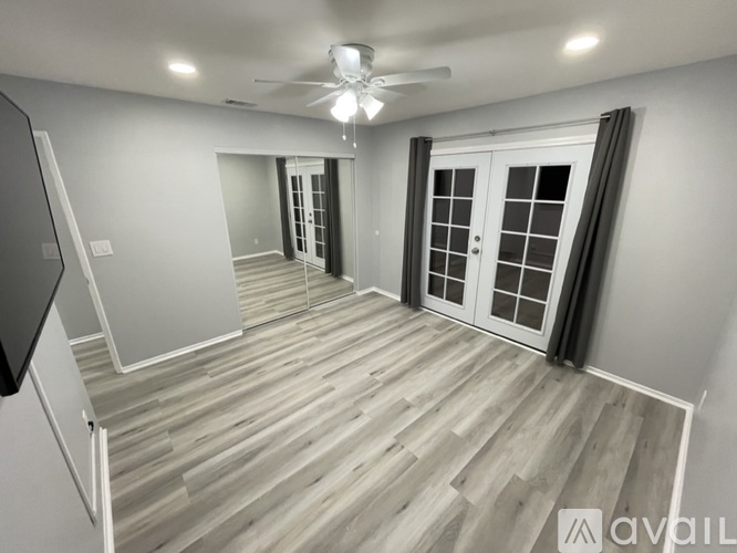 A spacious room with a television mounted on the wall and a wooden floor.