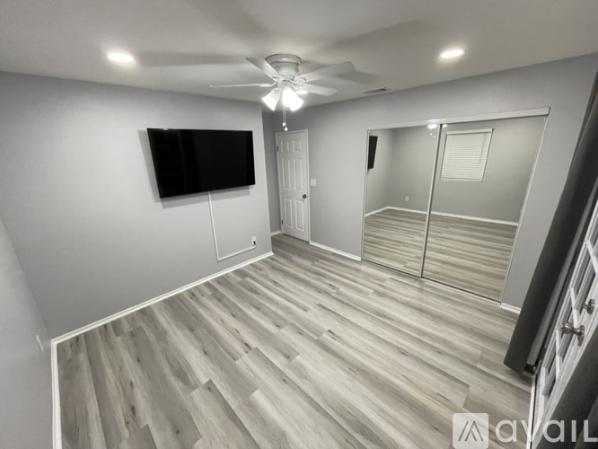 A spacious room with wooden flooring and a ceiling fan.