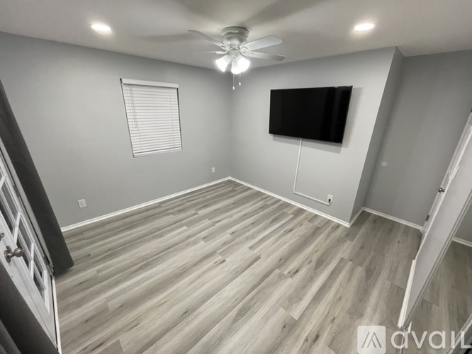 A room with a ceiling fan and a window with blinds.