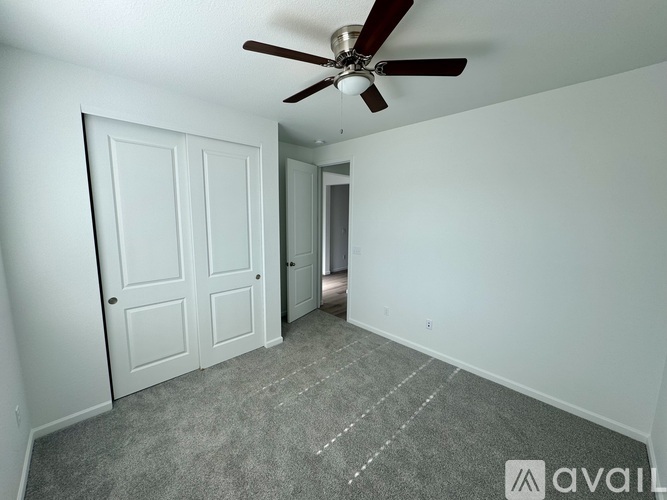A room with a ceiling fan and carpeted floor.