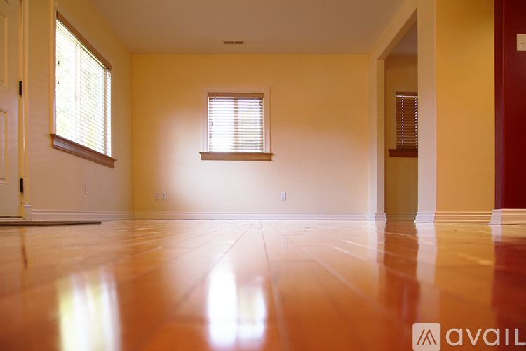 A room with wooden floors and a window with blinds.