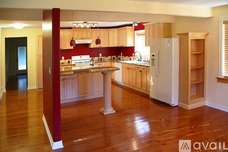 A kitchen with wooden floors and a white refrigerator.