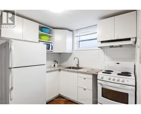 A white kitchen with a stove, sink, and cabinets.