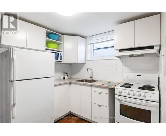 A white kitchen with a stove, sink, and cabinets.