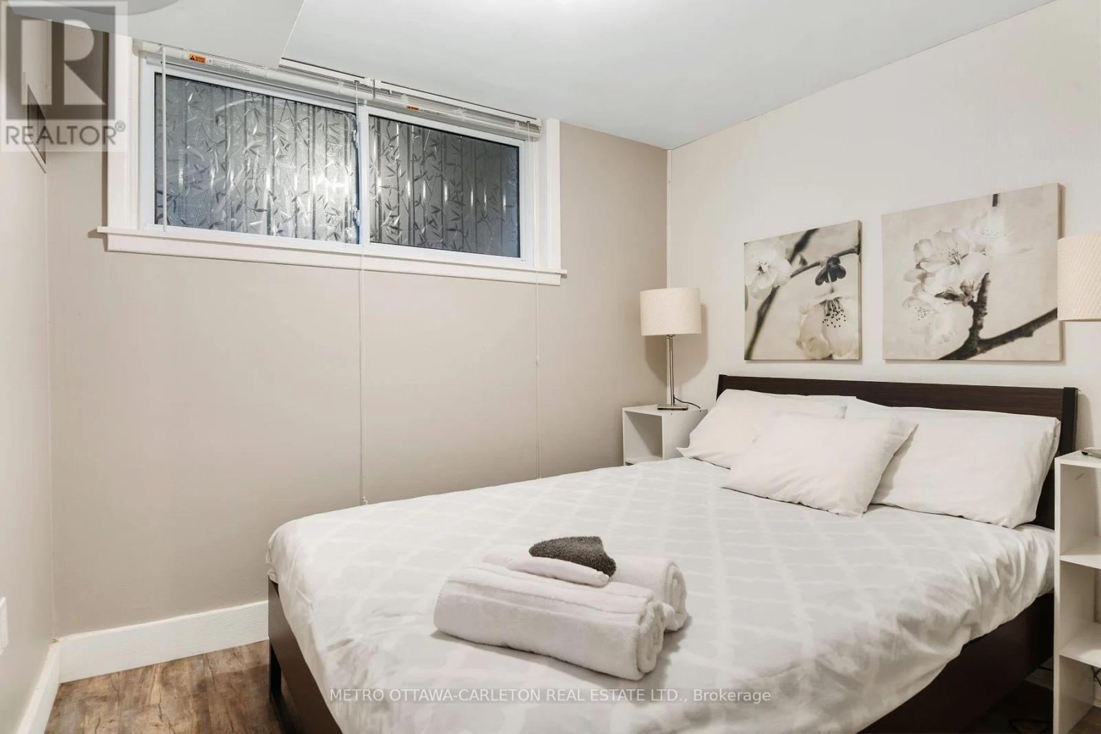 A bedroom with a bed, two lamps, and a window.