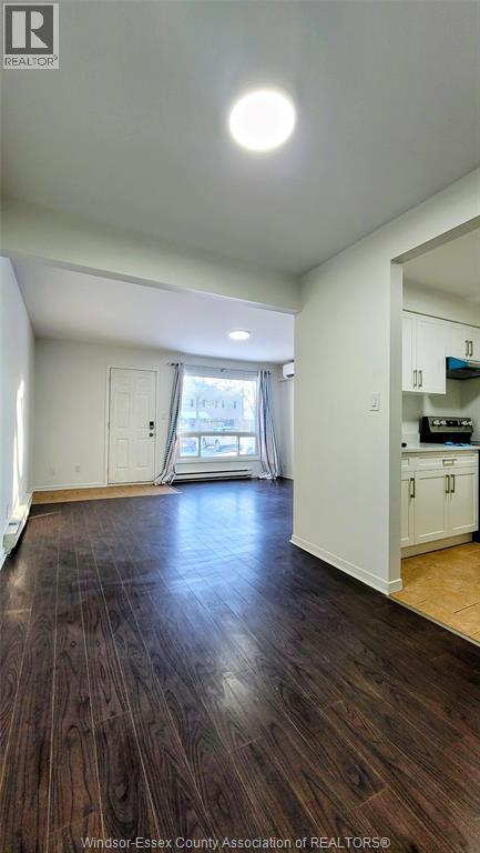 A spacious room with wooden floors and white walls.