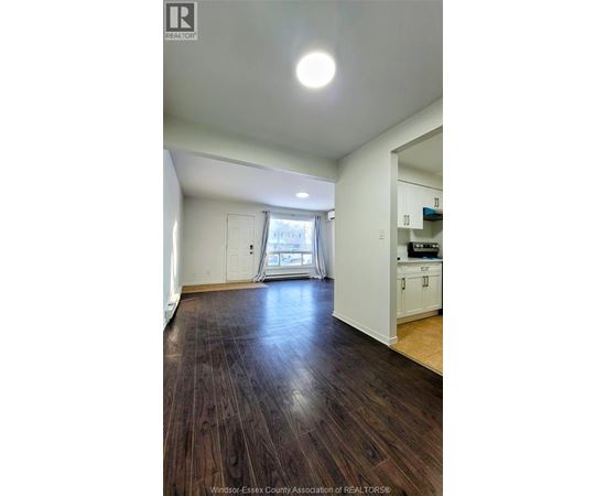A spacious room with wooden floors and white walls.