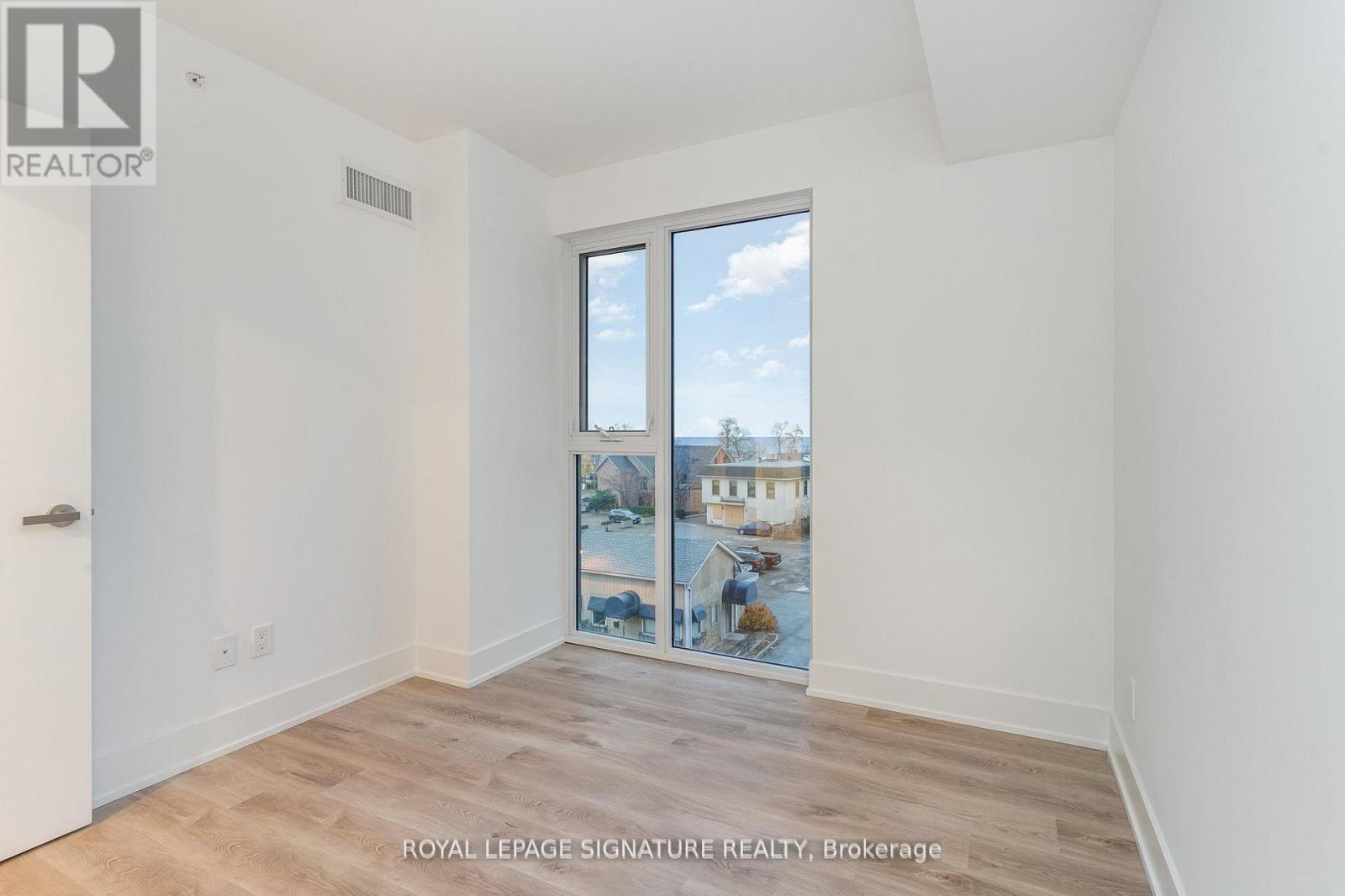A white room with a wooden floor and a window showing a view of the city.