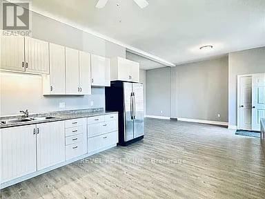A kitchen with white cabinets and a black refrigerator.