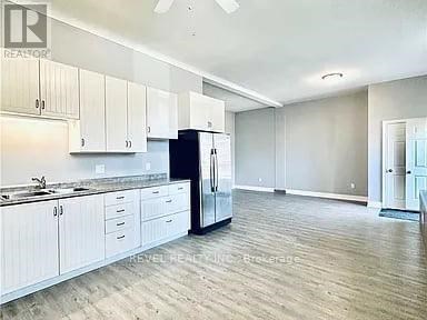 A kitchen with white cabinets and a black refrigerator.