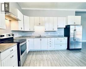 A kitchen with white cabinets and a black refrigerator.