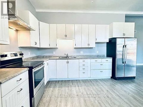 A kitchen with white cabinets and a black refrigerator.