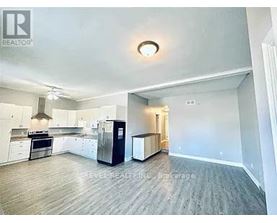 A spacious kitchen with white cabinets and a black refrigerator.