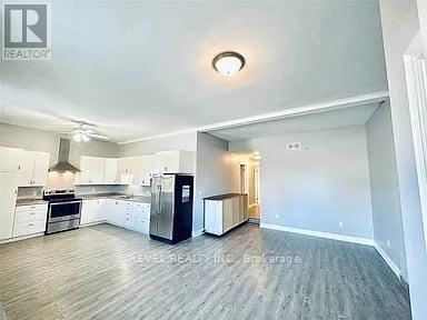 A spacious kitchen with white cabinets and a black refrigerator.