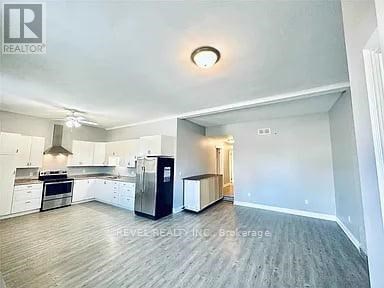 A spacious kitchen with white cabinets and a black refrigerator.