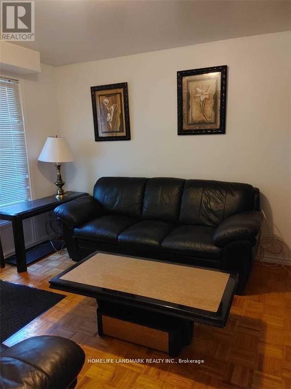 A black leather couch with a glass top table in front of it.