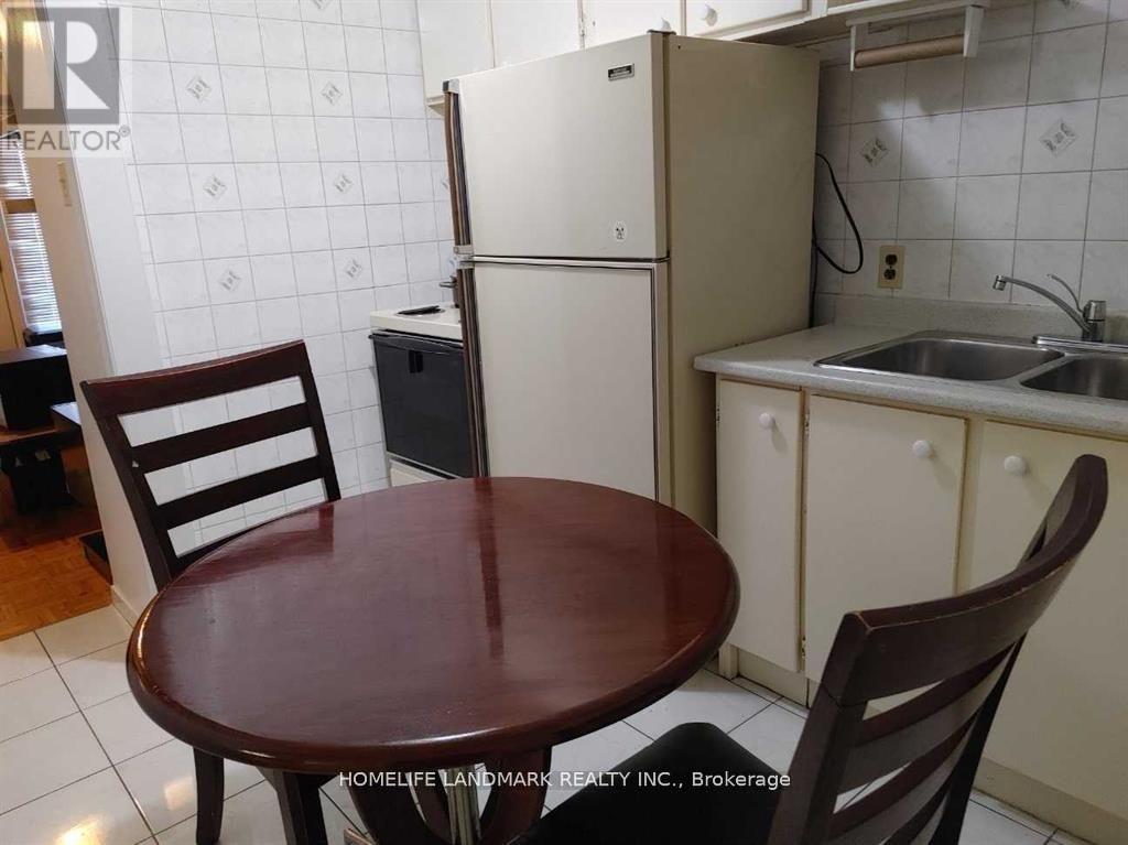 A kitchen with a table and chairs and a fridge.