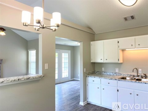 A kitchen with white cabinets and a marble countertop.