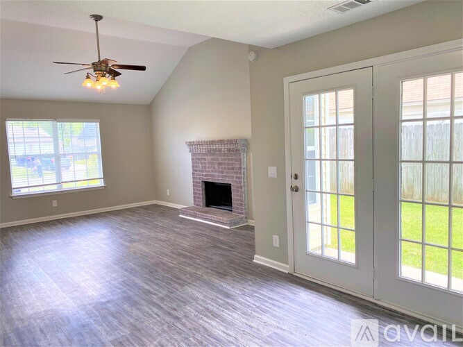 A spacious living room with a fireplace and a ceiling fan.