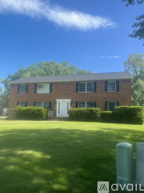 A house with a white door and windows surrounded by green grass.