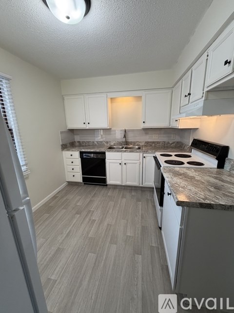 A kitchen with white cabinets and a marble countertop.