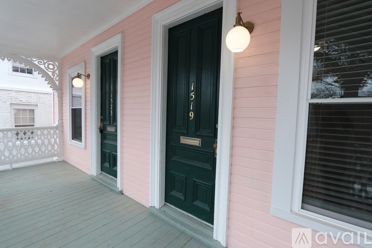 A pink house with a black door and a window with blinds.
