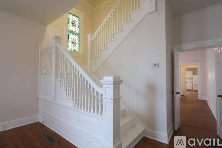 A staircase with a white railing and a stained glass window above it.