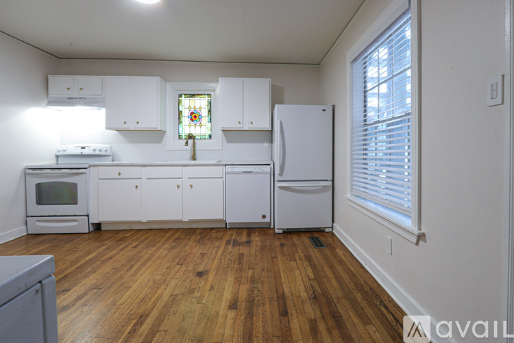 A kitchen with white cabinets and a wooden floor.