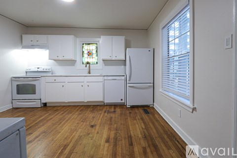 A kitchen with white cabinets and a wooden floor.