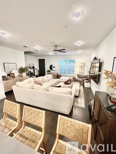 A living room with a white couch and wooden chairs.